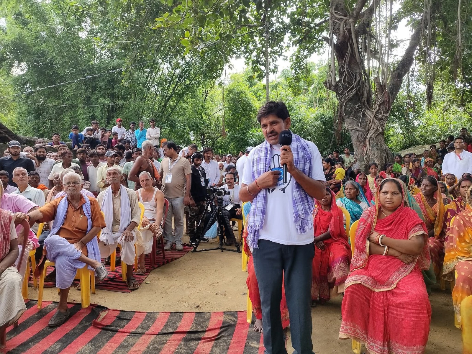Rahul Gandhi interacts with villagers in Nawada after halting his Voter Adhikar Yatra convoy, as crowds gather and workers climb on a JCB to see him.