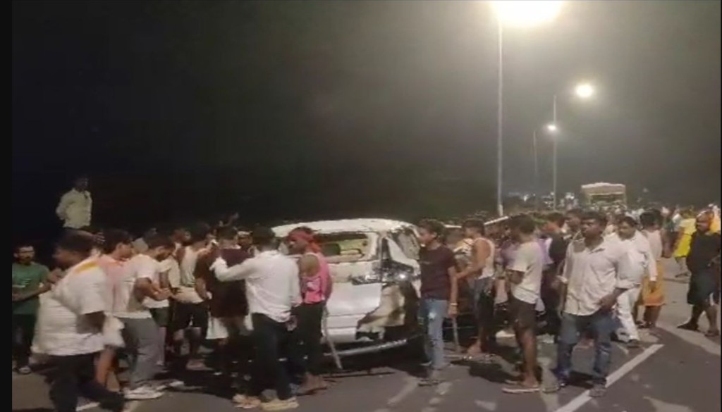 A damaged motorcycle and car on the Dargah-Bidupur bridge in Patna, with local residents gathered around protesting the accident.