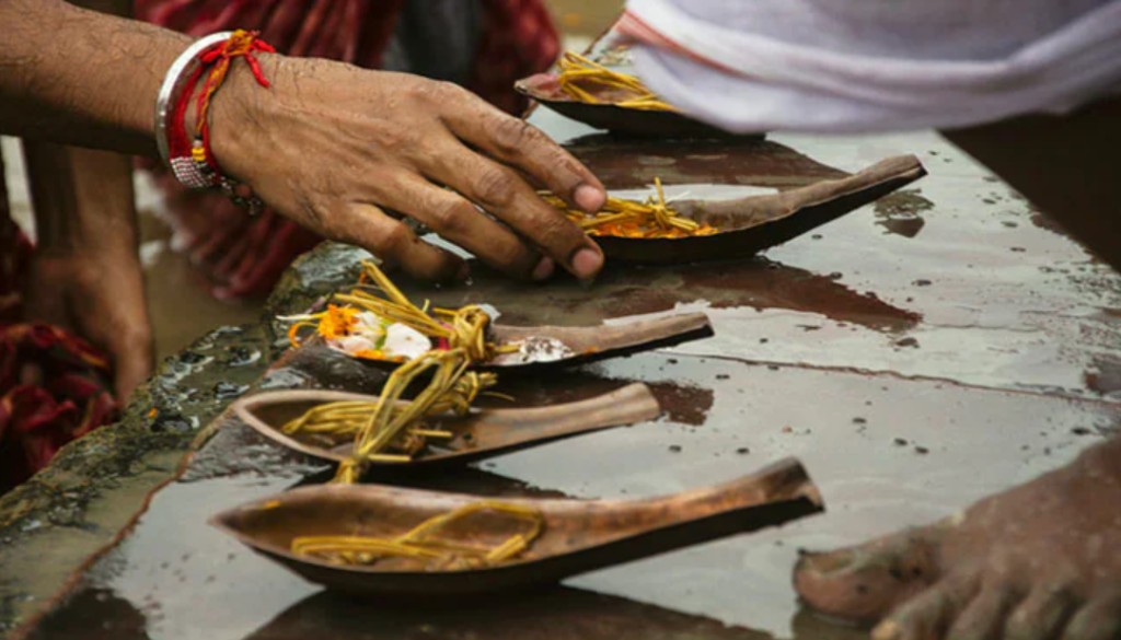 A priest performing ancestral rituals during Pitru Paksha, offering prayers and water oblations to honour forefathers.