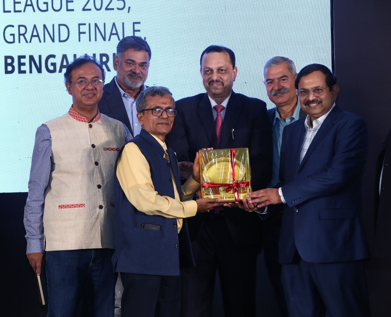 IXL 2025 Champion Ramki Krishnan receiving trophy from Mr. Vivek Kumar Singh, Chairman RERA Bihar, Mr. Ranjan Biswas, MD Ernst & Young India, Prof. Debabrata Das, Director IIIT Bengaluru, Mr. Amar Pandey, IPS Retd (President Crossword Association of Karnataka) and Mr. Ochintya Sharma.